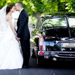 Mariés à côté d'une voiture de luxe